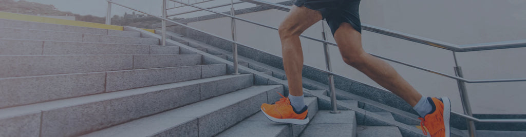 A person wearing orange shoes running up some stone stairs.