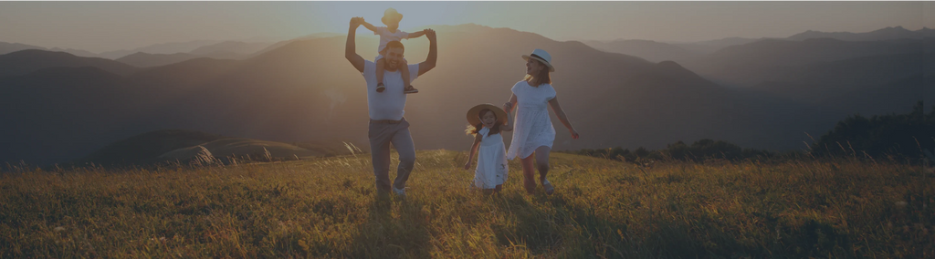 A family of four outside in a field with mountains in the background.