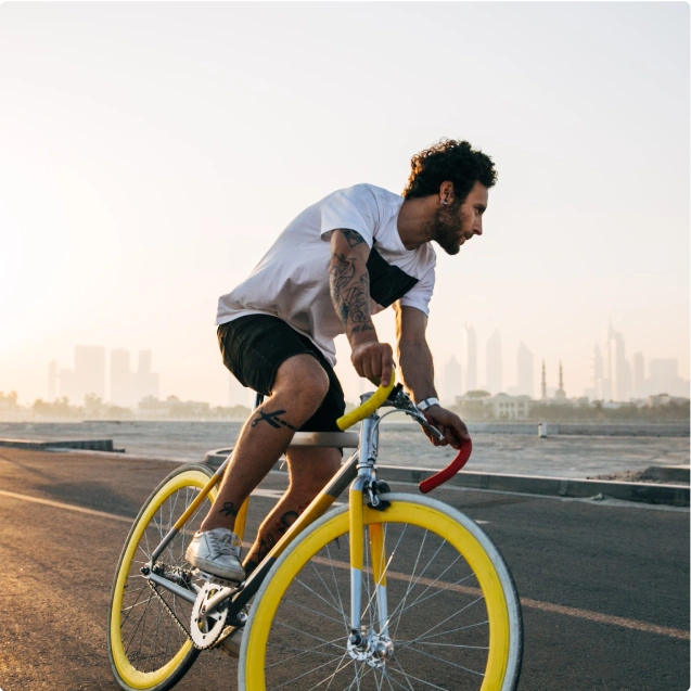 A man riding a bicycle with a city skyline in the background.